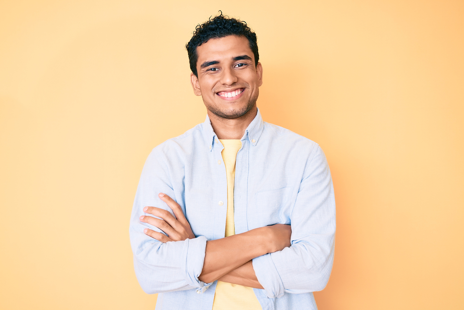 Young handsome hispanic man standing over yellow background happ