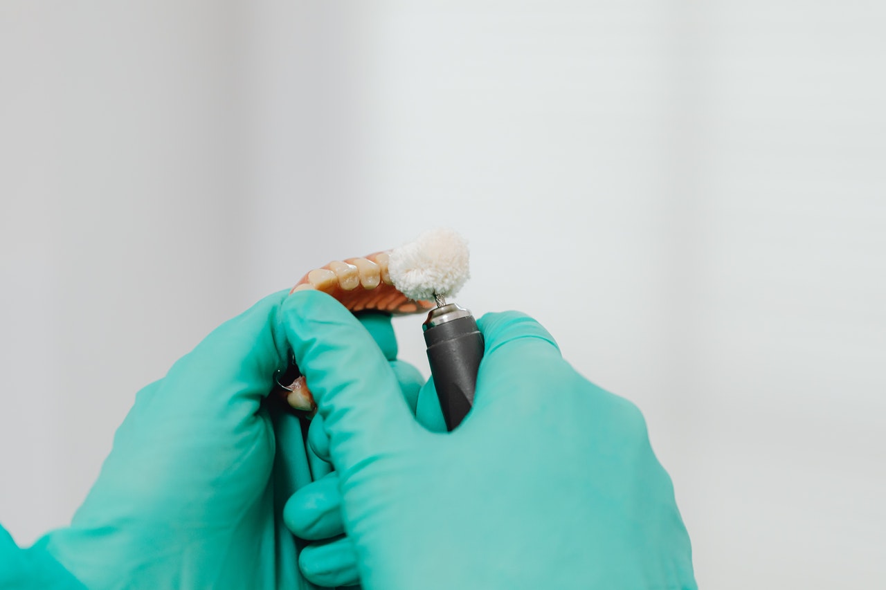 Close-Up-Shot-of-a-Person-Polishing-a-Denture implants face smile